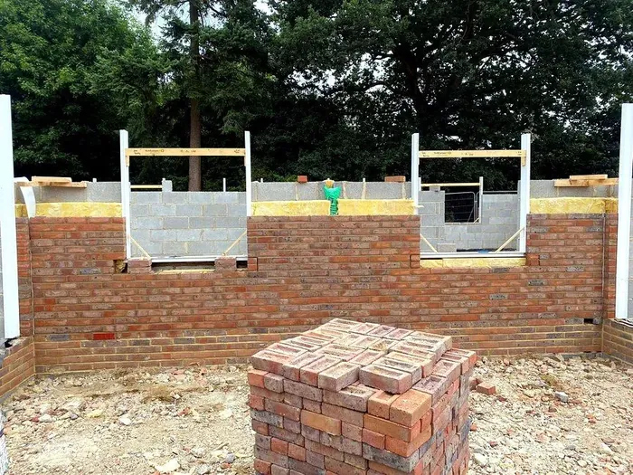 Brick and blockwork walls under construction with window openings framed